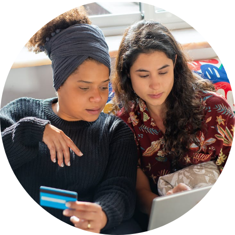 Two women looking at a tablet with a credit card in hand