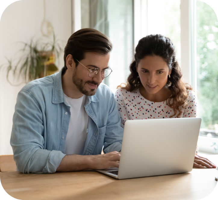 a man and a woman sitting on a table with a laptop